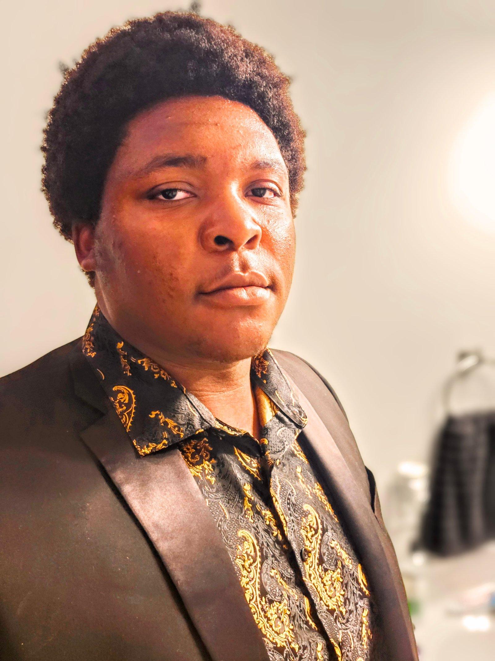 D'Onthony Johnson in a black and gold shirt and blazer